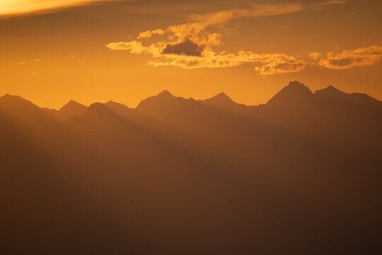 View of radiant sunbeams piercing through the peaks, painting the landscape in hues of gold and amber, Tiers, Trentino-South Tyrol, Italy.