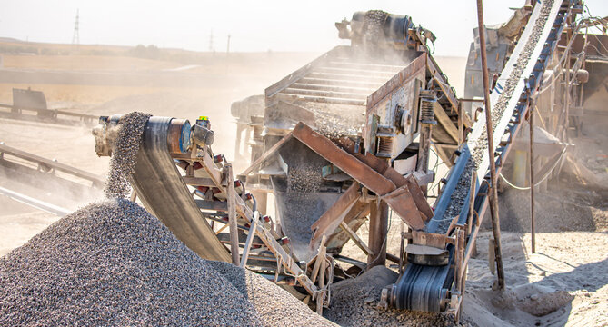 Vibrating screen stone crusher in operation. Crushing stones in a quarry for processing minerals, cement, limestone. Heavy and mobile equipment in a quarry for processing stone into building material.