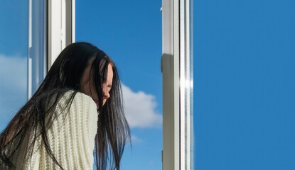 A young girl poses near a window in a house