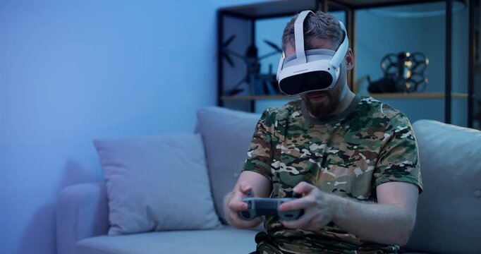 Immersive gaming victory: man in camo attire use rc for training simulation fly on FPV drone in VR glasses.
