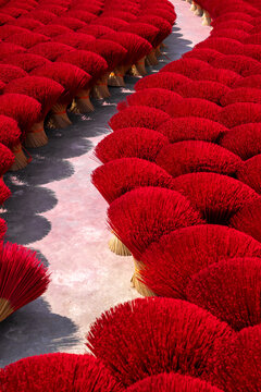 Aerial view of vibrant red incense sticks bundled and laid out in rows, creating a striking contrast against the ground, Ung Hoa, Ha Noi, Vietnam.