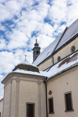 Fototapeta premium Snowy Medieval Saint George Church With Stone Tower, Snow-Covered Roof, And Clear Blue Sky, Ptuj, Slovenia