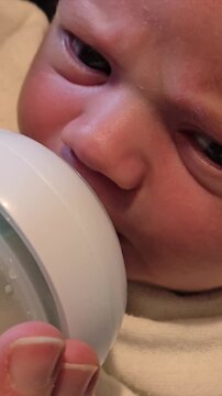 Extreme close-up of a newborn baby face while bottle feeding, infant drinking milk from a bottle, parenthood, childhood, baby healthcare, nursing, and newborn care. Video 4k