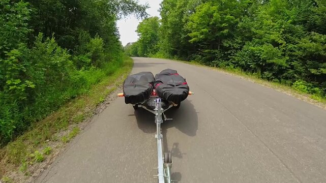 Kayaks on boat trailer with kayaks covered with waterproof dustproof UV protection fabric, transported by truck or car. Water sport fishing. Going to boat launch at lake. Boat trailer fishing kayaks.
