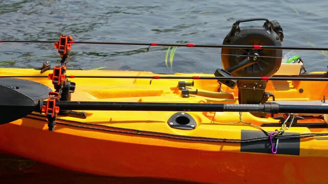 Fully rigged kayak watercraft mooring and tied to boat pier near cottage. Recreational watercraft, kayaking lake during tournament or fishing derby. Kayak water craft equipment for fishing activities.
