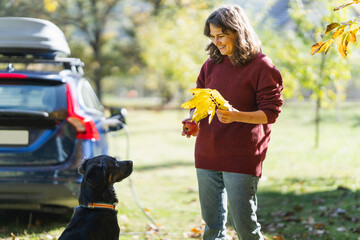 Woman with her dog next to charging electric car