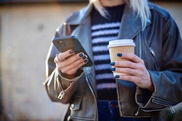 Fototapeta premium Young Woman Using Smartphone While Holding Coffee