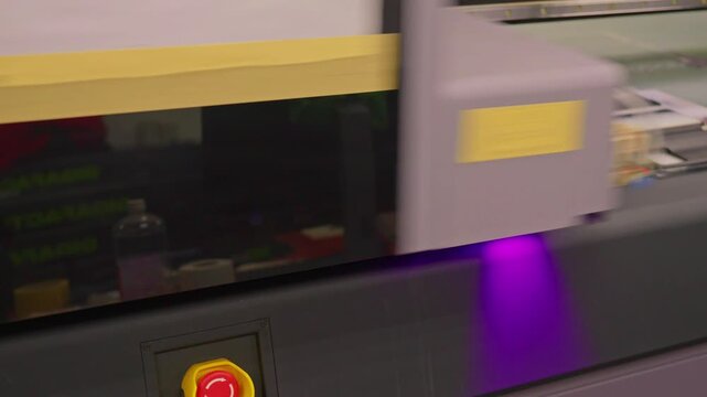 4K footage of a UV printer simultaneously printing an image on ten mobile phone cases. High-tech digital printing process in factory or studio environment, showing precision and automation.