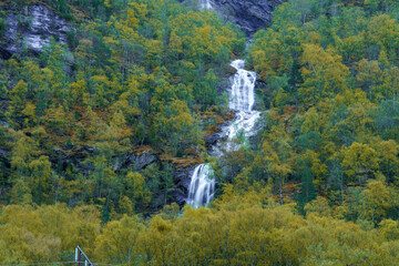 Tall Mountain Waterfall Flowing Through Forested Valley in Norway