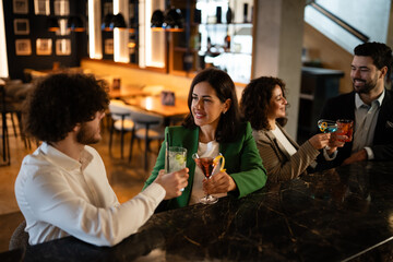 Friends socializing, drinking cocktails at a bar