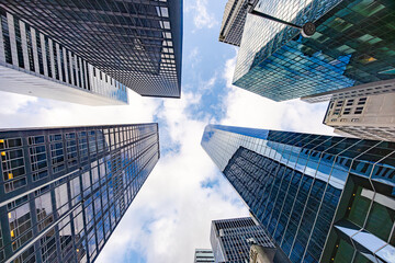 Fototapeta premium Low angle view of modern skyscrapers in New York City forming symmetrical urban canyon against blue sky in Manhattan business district
