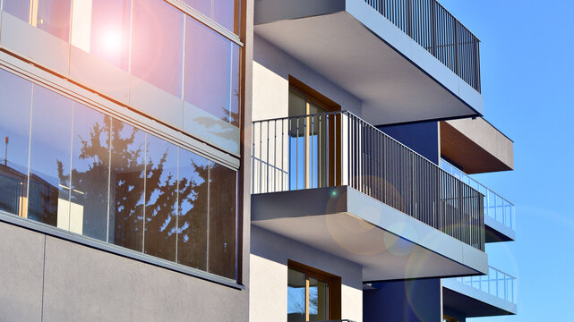 Concept of urban living and modern architecture. View of modern residential building with glass balconies and white facade. Contemporary apartment building in European city. 