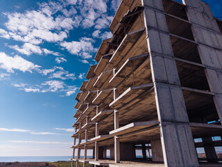 Fototapeta premium Unfinished hotel building near coastline. Abandoned concrete hotel structure rises above the coastal landscape.