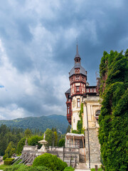 Peles Castle tower detail. Close view of Peles Castle tower with decorative elements and cloudy sky © Vadim