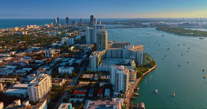 Approaching high-rise buildings of hotels at the picturesque waterfront. View on the numerous vessels on the waterscape. Drone footage over Miami, Florida, USA.