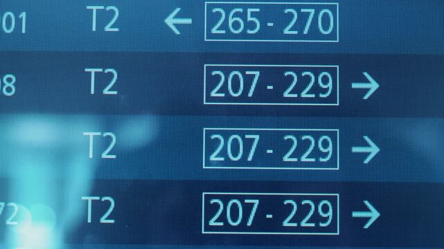 Digital display board showing flight information with terminal numbers and gate directions, highlighting continuous updates in a busy airport environment