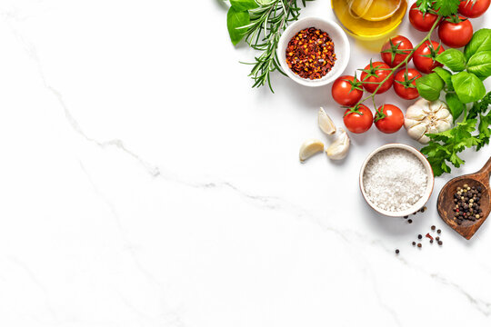 Fresh cooking ingredients and seasonings on a bright marble background top view with blank space for your text, menu or recipe concept