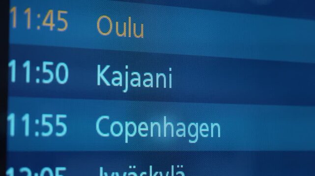 Flight schedule display board showing departure times for Kemi/Tornio, Oulu, Kajaani, Copenhagen, and Jyvaskyla in a modern airport terminal setting