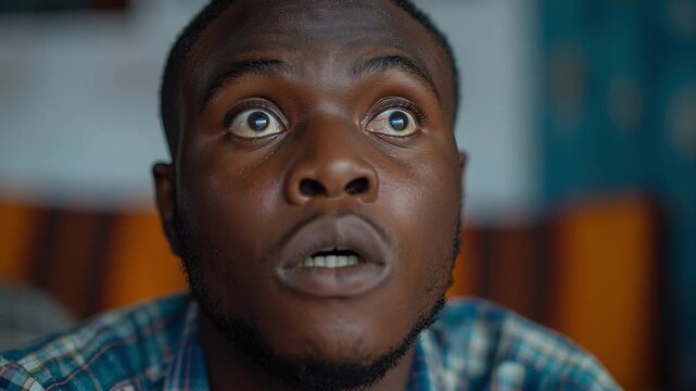 A man looks up with wide eyes and an open mouth, expressing shock during a discussion. This interaction happens inside a home in the evening time