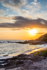 Obraz premium landscape of black sea sandy beach at sunrise. golden sand and rocks on the coast of bulgaria. beautiful view with sun above horizon. european summer vacation season and leisure concept