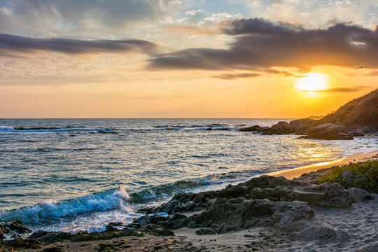 landscape of black sea sandy beach at sunrise. golden sand and rocks on the coast of bulgaria. beautiful view with sun above horizon. european summer vacation season and leisure concept