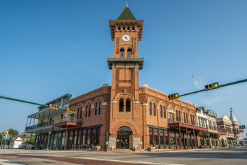 Red Brick Building With Tall Clock Tower and Shops Along Sidewalk in Downtown Grapevine, Texas With...
