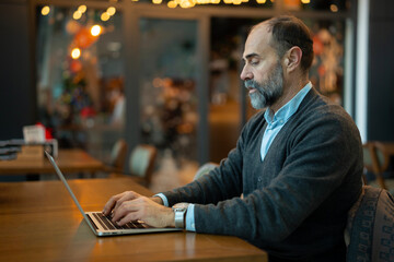 Fototapeta premium Mature man working on laptop in cafe