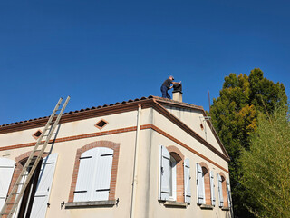 Person repairs chimney on roof of house