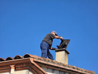 Worker fixes chimney on top of house during day