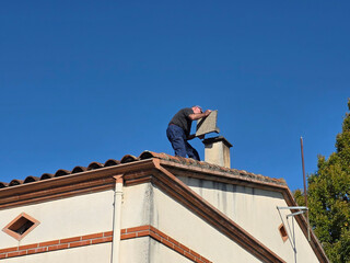Man repairs chimney on a sunny roof