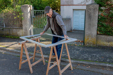 Man is assembling a wooden frame on saw horses on the street