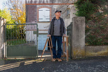 Person holds sawhorses near a home with a gate in the yard