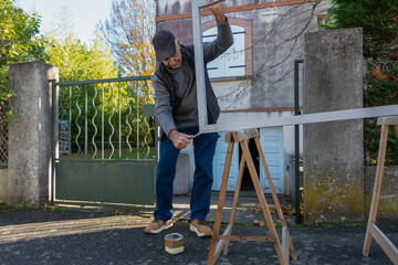 Person works on painting a wooden frame outside their home