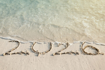 Handwritting inscription numbers 2026 on perfect tropical sandy beach