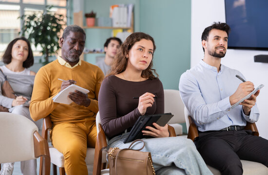 In lecture meeting, young woman listen to teacher, write down summary. Language courses, exam preparation, lectures and practical classes at school. Students are taking trial class in language courses