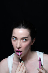 Obraz premium Woman applying makeup lipstick dark backdrop modern beauty aussie slickback hair ponytail pink lipstick matte lips