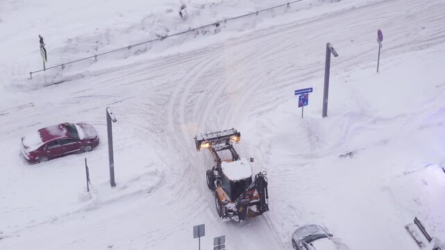 Front loader clearing snow on a city road during winter, municipal snow removal, road maintenance work, cold weather conditions and urban transportation infrastructure concept