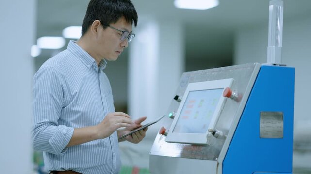 Engineer operating industrial equipment with touch screen interface in factory setting