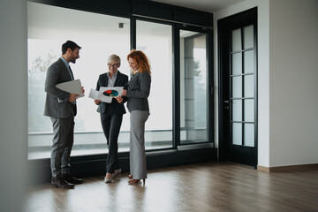 Wide shot of a diverse group of business professionals standing in a modern open-plan office, engaged in a friendly conversation and networking
