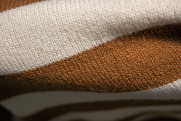 A knitted blanket with a brown and white pattern. The blanket is made of wool and has a cozy, warm feeling