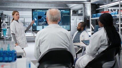 Obraz premium Medical school professor holding seminar on advanced cell biology for students. Academic expert explaining microscopic cell division processes using digital screen in laboratory, camera B