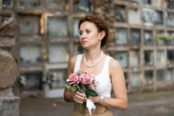 Fototapeta premium Sad woman remembers deceased relative at cemetery