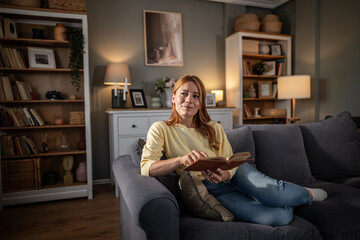 Woman enjoying leisure time reading book on couch © Migma_Agency