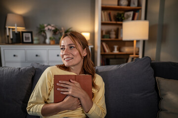 Obraz premium Woman enjoying reading a book at home on sofa