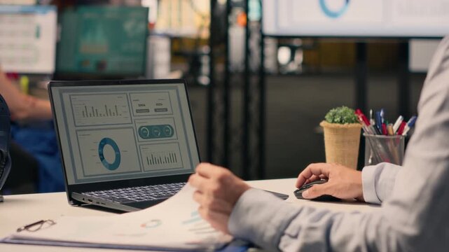 Professional worker reviewing compliance data on laptop screen at desk, ensuring performance review and doing risk assessment in office. Visual data for business intel support productivity.