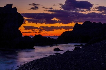 室戸岬の海岸で見た夕焼けに染まる岩場の海岸線とドラマチックな雲の風景