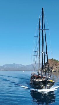 Elegant gulet sailing on calm blue sea with distant mountains under clear sky