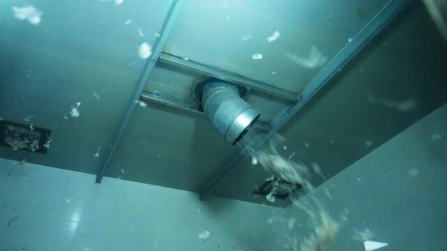 Close-up of water droplets splashing from a ventilation duct on a metallic ceiling