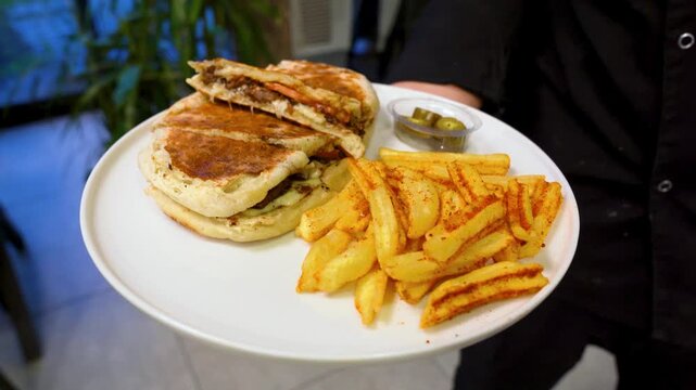 Waiter Serving Bazlama Sandwich with Melted Cheese and French Fries