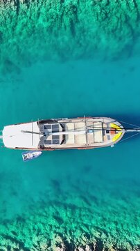 Aerial view of a traditional wooden gulet anchored in crystal clear turquoise Mediterranean waters